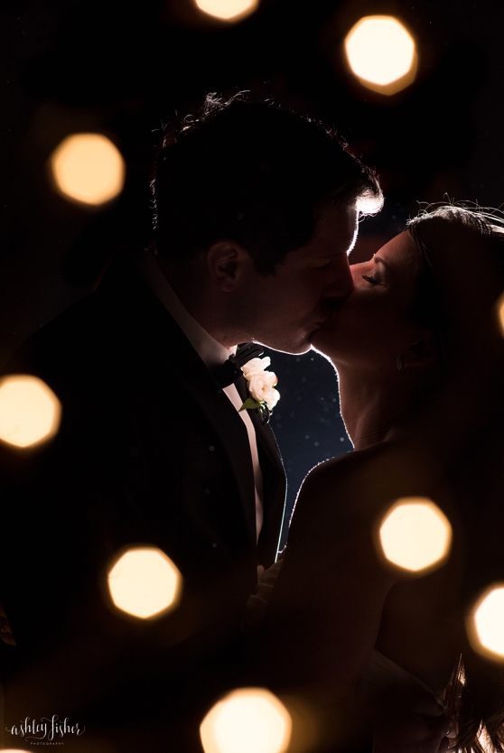 Photo of bride and groom kissing with back lighting at a wedding at the World's Fair Pavilion in Forest Park.