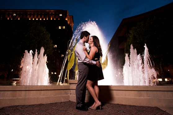 Night photo of couple standing in front of fountain in downtown Clayton engagement session 