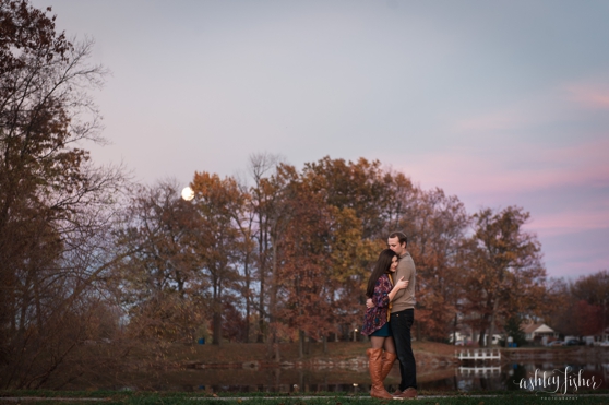Photo of a couple hugging in front of fall trees and purple sky at engagement session
