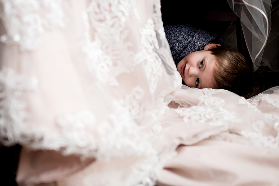 ringbearer hiding under the bride's dress for a winter wedding at graham chapel by ashley fisher photography