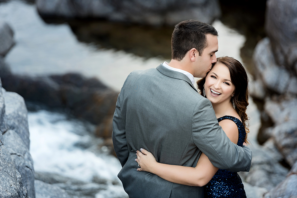 bride laughing while groom kisses her on the temple at johnson's shut ins engagement session