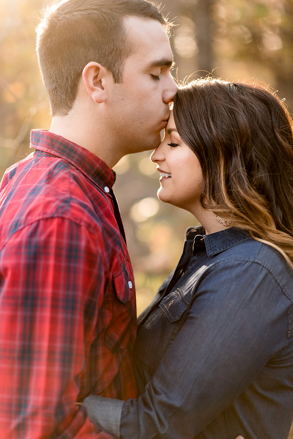 husband kissing wife on forehead during fall engagement session at elephant rock