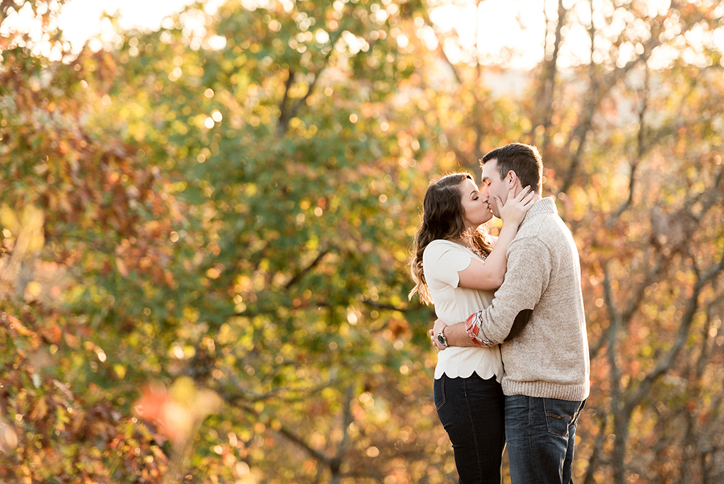 couple kissing among fall color leaves at elephant rock engagement session
