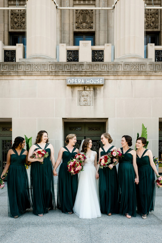 bridesmaids in green dresses walking with bride outside of stifel theater