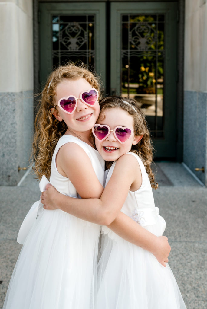 flower girls hugging wearing heart shaped sunglasses